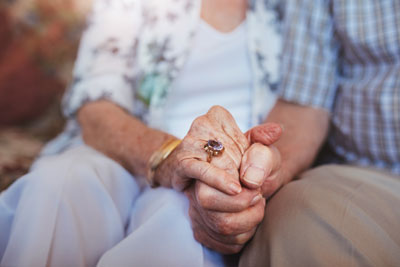 elderly couple clasping hands